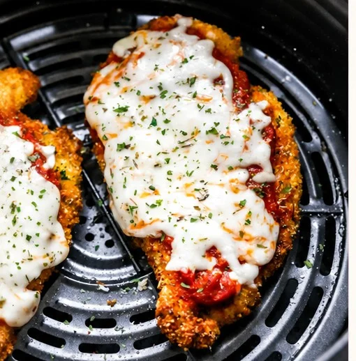 Crispy healthy chicken Parmesan made in an air fryer, garnished with fresh basil.