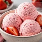 Delicious bowl of homemade strawberry ice cream topped with fresh strawberries