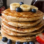 Stack of high protein Kodiak pancakes topped with fresh berries and syrup